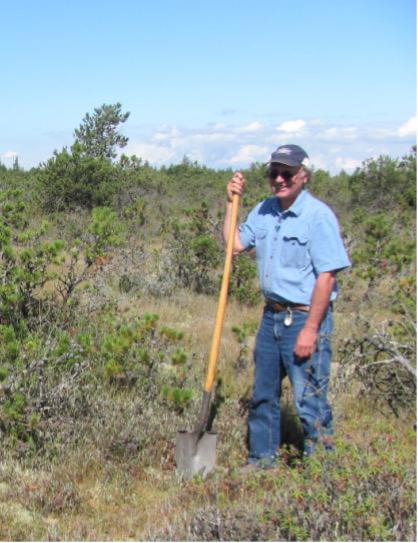 Man holding a shovel in a bog.