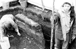 Two women digging through an archeological site.